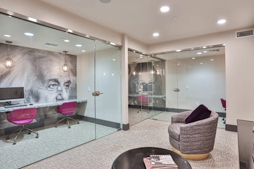 a large office area with glass walls and a desk with a chair and a table