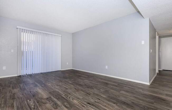 A room with wooden flooring and a window with blinds.
