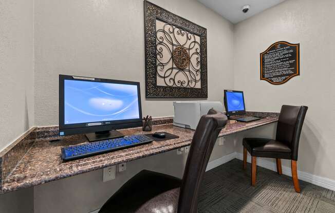 a computer desk with two computers and two chairs