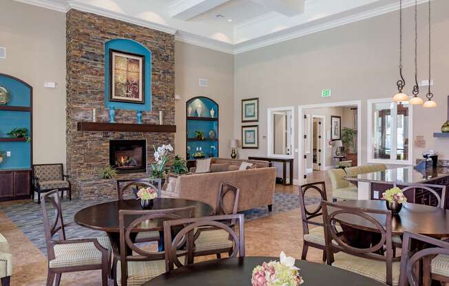 A room with a stone fireplace and a dining table set for six.