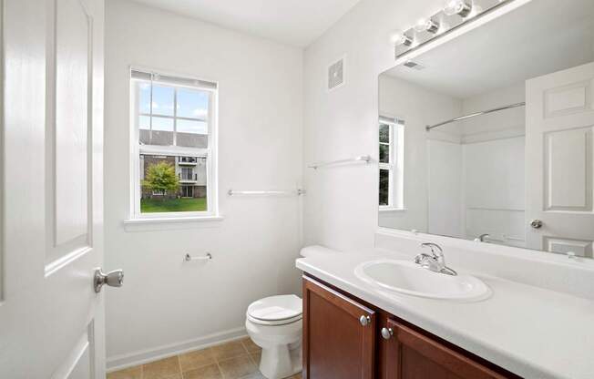 A white bathroom with a toilet, sink, and mirror.