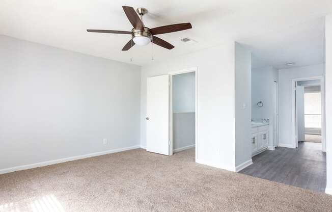 an empty living room with a ceiling fan and a bathroom