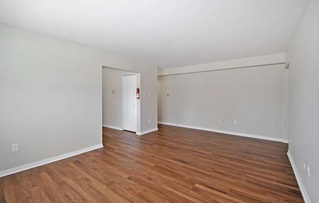 the spacious living room with wood flooring and white walls