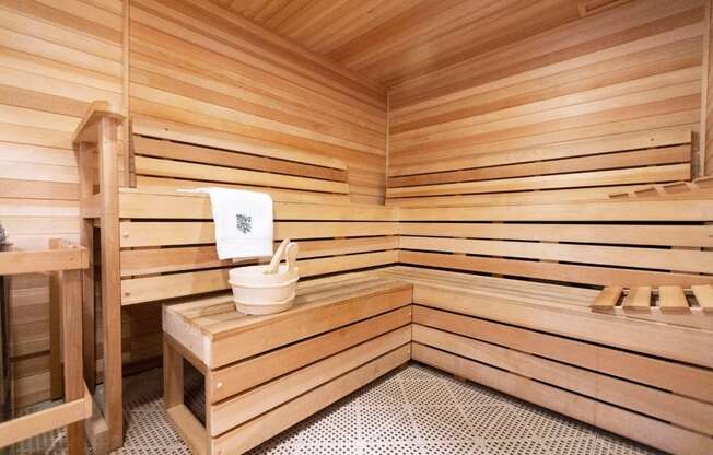 a sauna with a wooden bench and a bucket in it