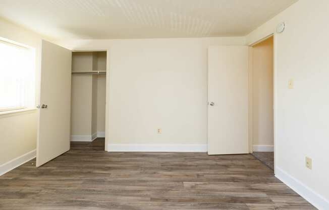 a bedroom with white walls and a wooden floor