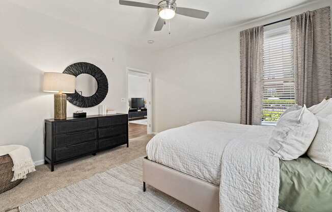 A bedroom with a bed, dresser, and window.