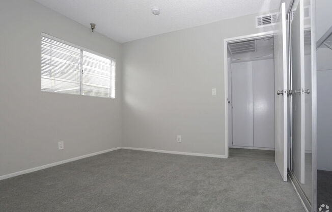 an empty bedroom with a closet and a window  at The Marq Apartments LLC, California
