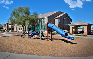 a playground with a blue slide in front of a building