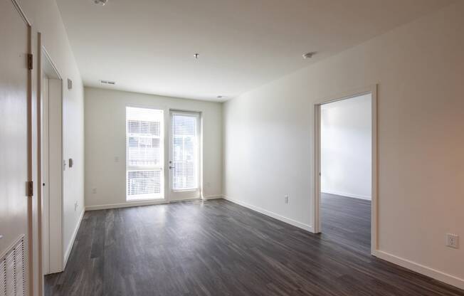 an empty living room with wood floors and white walls