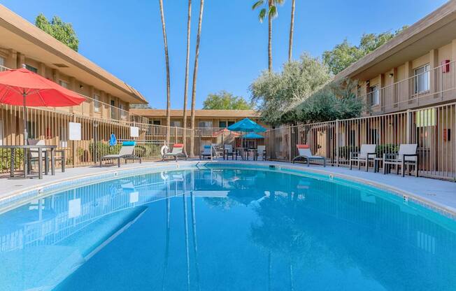 A large swimming pool in a resort with sun loungers and umbrellas.