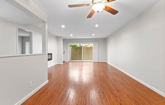 a living room with white walls and a ceiling fan