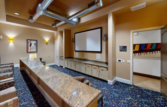 a large room with a long counter and a projector screen on the wall