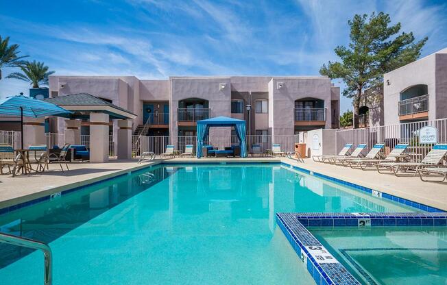 A swimming pool in front of a building with a blue sky in the background.