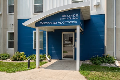 a blue building with a door and a sign that says warehouse apartments