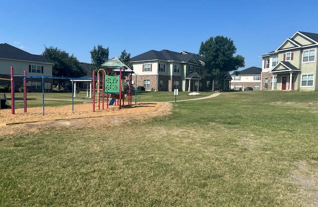 a playground in a park with houses in the background