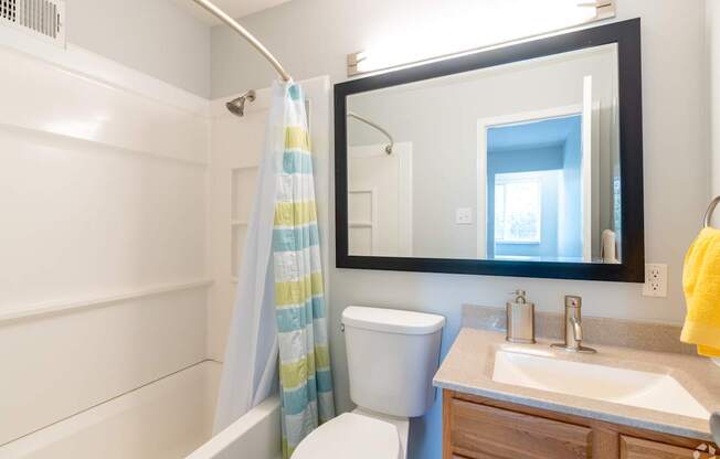 A bathroom with a toilet, sink, and shower curtain.