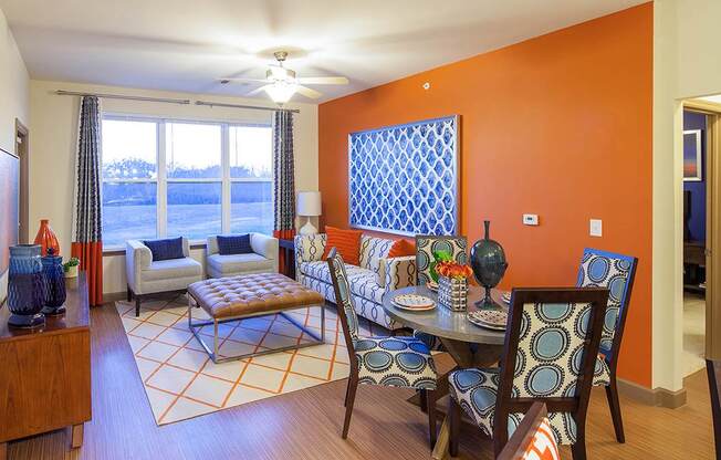 a living room with orange walls and a dining room with a table and chairs