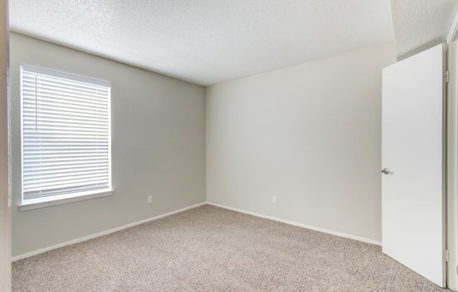 an empty room with a white door and a window