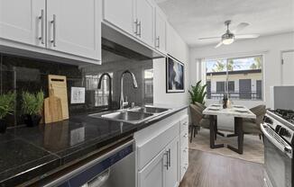 a kitchen with white cabinets and a black counter top at Pacific Rose, Los Angeles