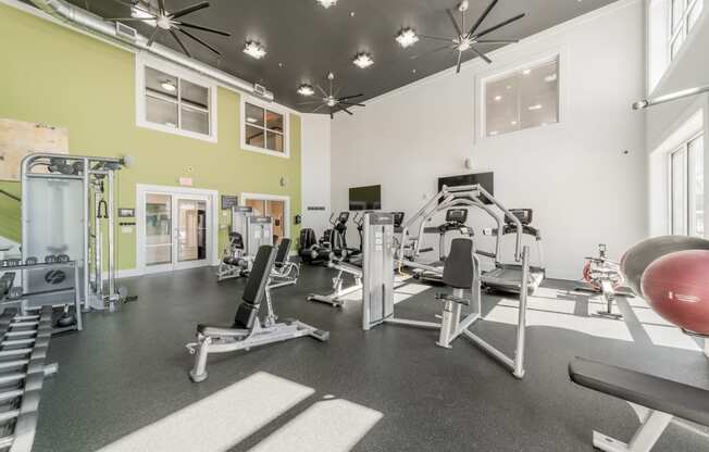 a spacious fitness center with exercise equipment and windows