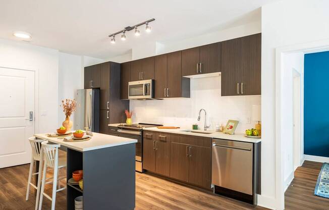 A modern kitchen with a white countertop and dark brown cabinets.at The Vale at the Parks, Washington, 20012