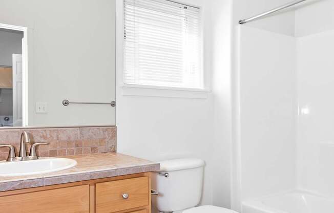 A white toilet sits in a bathroom next to a sink at The Landing Apartments and Townhomes, Oregon, 97045