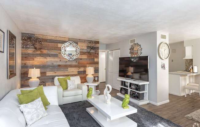 A living room with a white couch, a wooden wall, and a TV.