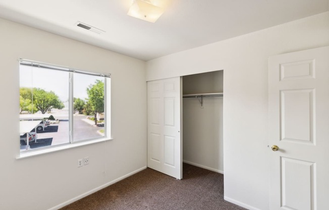 an empty bedroom with a window and a closet