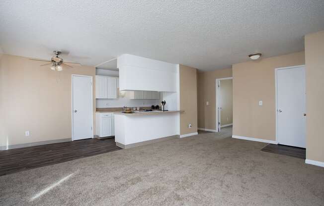 an empty living room and kitchen with a ceiling fan