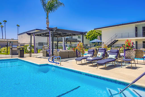 A pool with a blue water and chairs around it.