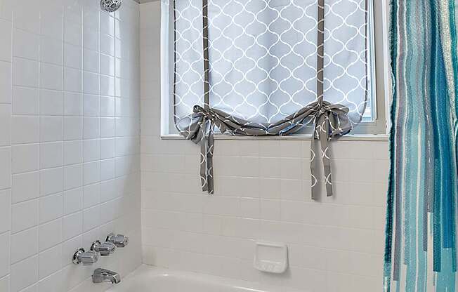 A white bathtub with a shower curtain tied in a bow.