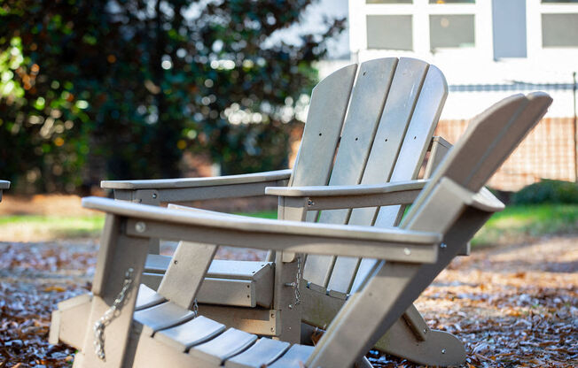 two wooden adirondack chairs in front of a house