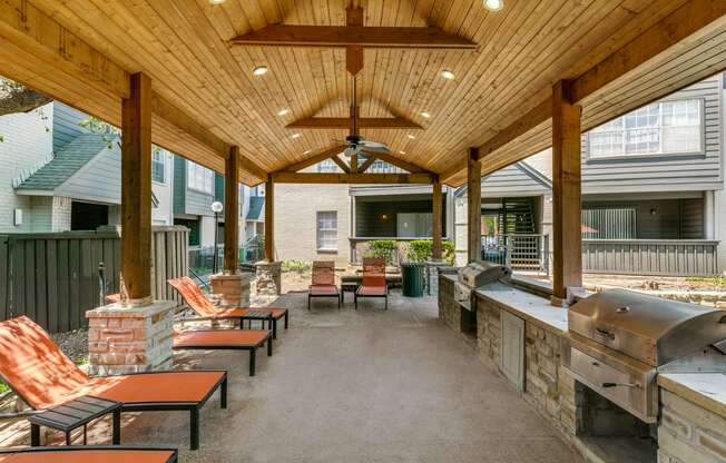 a covered patio with a grill and tables and chairs