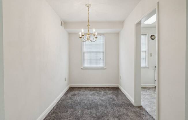 an empty living room with a chandelier and a window