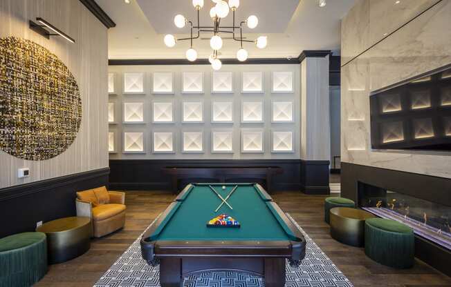 a pool table sits in the middle of a room with a fireplace and a chandelier