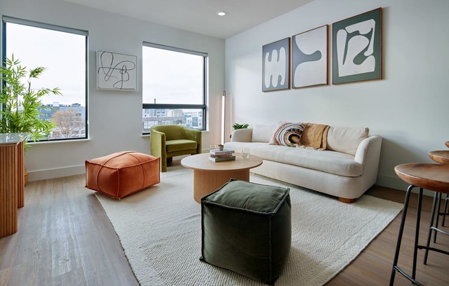 A living room with a white couch, a green chair, and a wooden table. at Glassworks, Philadelphia, Pennsylvania