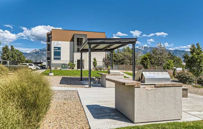 a picnic area with a grill and a building with mountains in the background