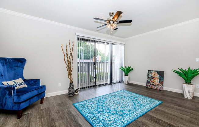 a living room with a blue chair and a ceiling fan