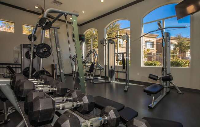 A gym with a variety of equipment including dumbbells, weight machines, and benches.
