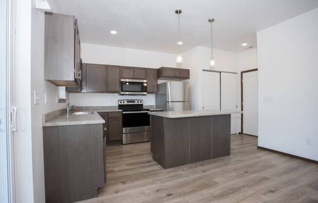 an empty kitchen with wooden floors and stainless steel appliances