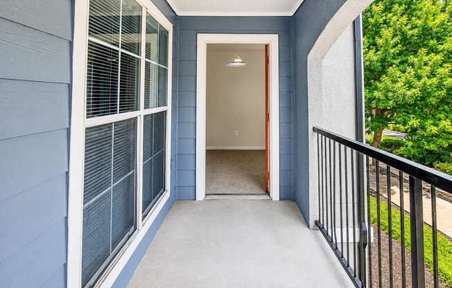 A blue house with a white door and a black railing.