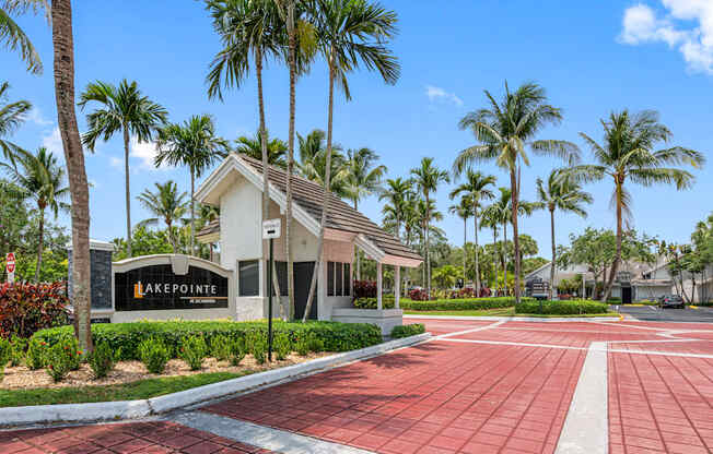 a building with palm trees in front of it and a red sidewalk
