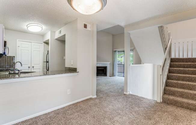 a living room with a staircase and a kitchen in the background