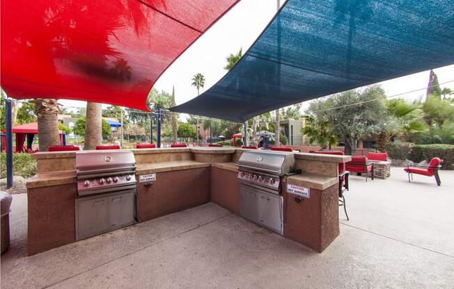 a patio with barbecue grills and umbrellas