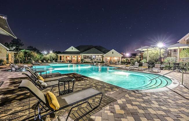 a swimming pool at night with chairs around it  at Waterstone at Cinco Ranch, Texas