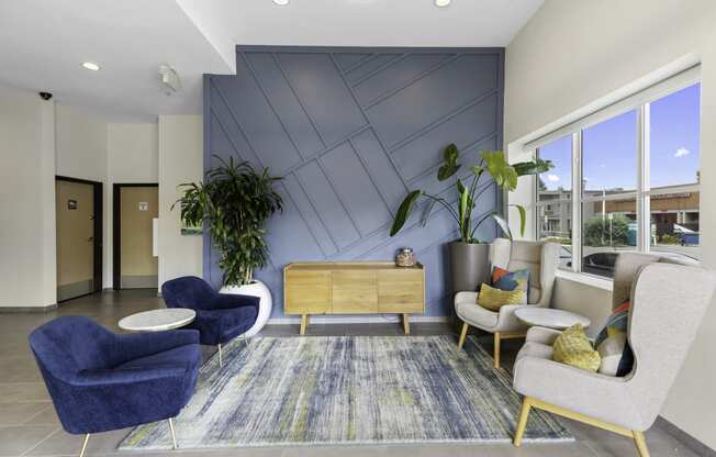 Cozy Lobby Seating Area with blue chairs and a yellow table in front of a textured blue accent wall at Arabella Apartment Homes, WA 98155