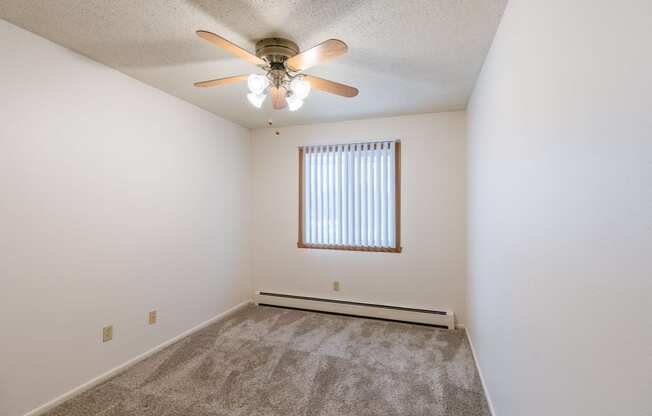 a bedroom with a ceiling fan and carpet. Fargo, ND Betty Ann Apartments