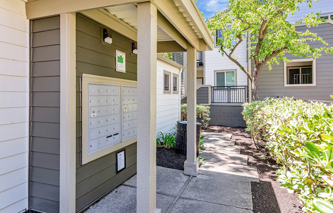 A grey house with a mailbox on the front porch.