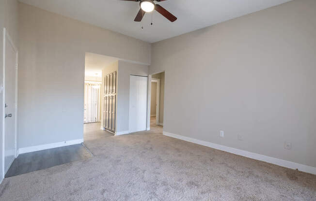 A room with a ceiling fan and carpeted floor.