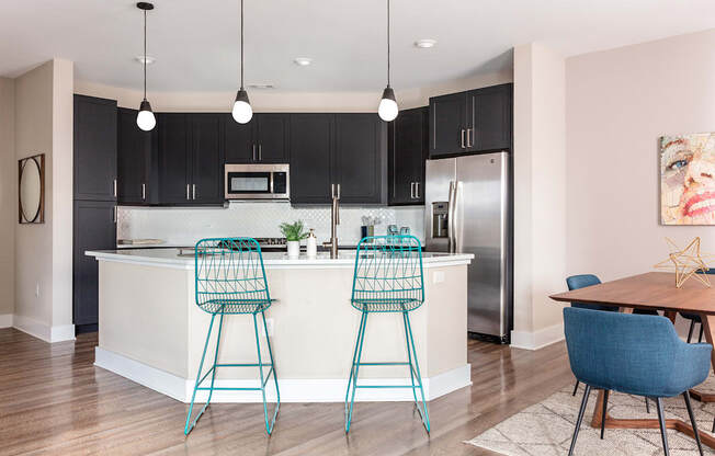 an open kitchen and dining area with bar stools in front of a kitchen island
